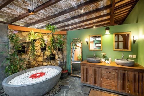 un bagno con due lavandini e una grande vasca di Villa Uma Anyar- Joglo Uma ad Ubud