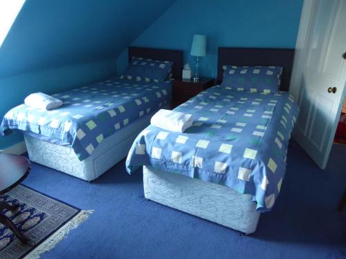 two beds in a room with blue walls at Seashells Guest House in Aberdeen