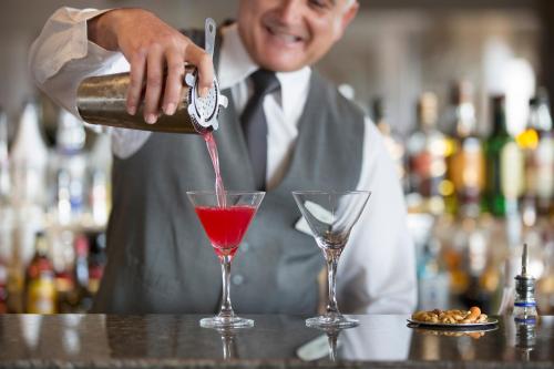 a man pouring a red drink into a martini glass at Alion Beach Hotel in Ayia Napa