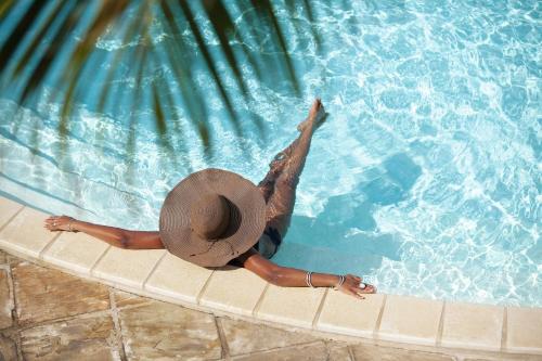 a woman in a hat in a swimming pool at Hotel Le Recif, Ile de la Reunion in Saint-Gilles-les-Bains