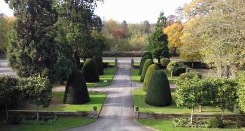 a pathway through a garden with trees and bushes at Great Fosters - Near Windsor in Egham