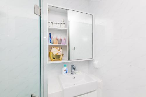 a white bathroom with a sink and a mirror at Dalian Shahekou·Peace Square· Locals Apartment 00162850 in Dalian