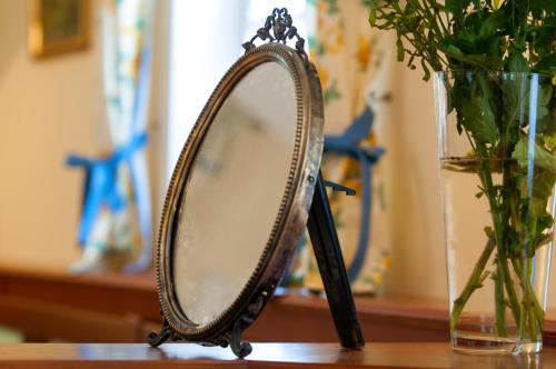 a mirror sitting on a table next to a vase at Babiččina Zahrada Penzion & Restaurant in Pruhonice