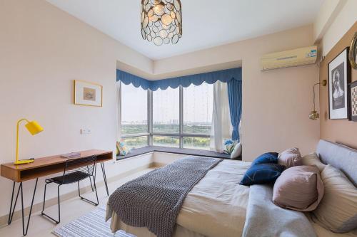 a bedroom with a bed and a desk and a window at Haikou Xiuying·Binhai Avenue· Locals Apartment 00164510 in Changliu