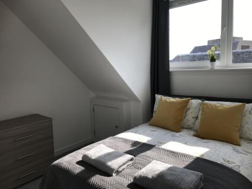 um quarto com uma cama com almofadas e uma janela em Carvetii - Edward House C - 2 Dbl bed 2nd floor flat em Dunfermline