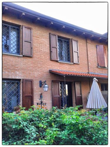 a brick house with an umbrella in front of it at La Corte del Macero in Castelfranco Emilia