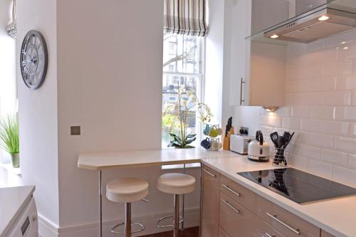 a kitchen with white walls and a counter with stools at Gresham 1-bed in Eastbourne