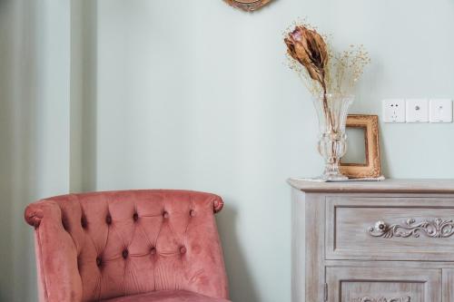 a red chair next to a dresser with a vase of flowers at [Roader] Wuhan Jianghan District, Xinhua Road in Wuhan