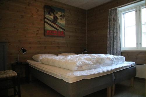 Una cama en una habitación con una pared y un cartel en Myrkdalen Resort Årmotssteien, en Vossestrand