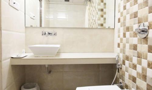 ein Bad mit einem Waschbecken und einem Spiegel in der Unterkunft Hotel Aaram Orchard in Ahmedabad