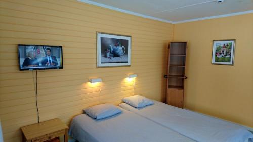 1 dormitorio con 1 cama y TV en la pared en Bollegården B&B en Bollnäs