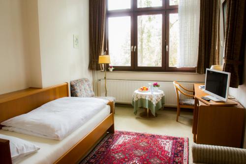 a bedroom with a bed and a desk with a computer at Hotel Haus am See in Bad Salzuflen