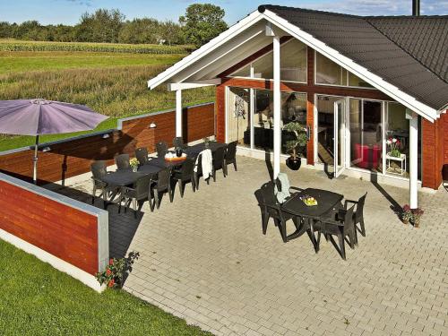 d'une terrasse avec des tables, des chaises et un parasol. dans l'établissement 16 person holiday home in Nordborg, à Nordborg