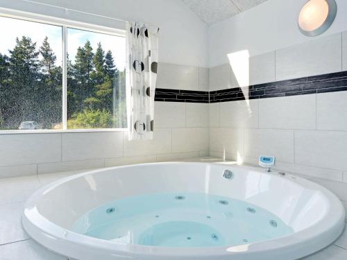 a large white tub in a bathroom with a window at 24 person holiday home in Bl vand in Blåvand