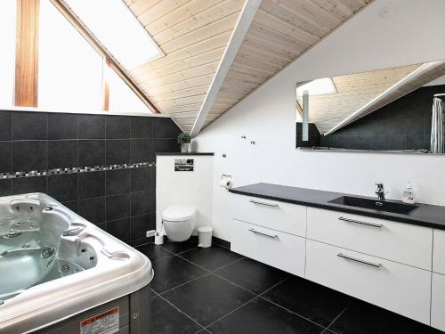 a bathroom with a tub and a sink and a toilet at Four-Bedroom Holiday home in Jerup 3 in Jerup