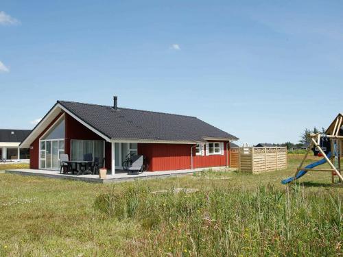 ein rotes Haus mit einem Spielplatz und einer Rutsche in der Unterkunft 9 person holiday home in Brovst in Brovst