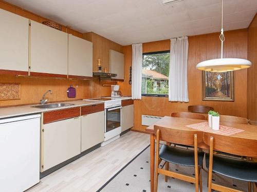 a kitchen with white cabinets and a wooden table at Two-Bedroom Holiday home in Væggerløse 24 in Marielyst