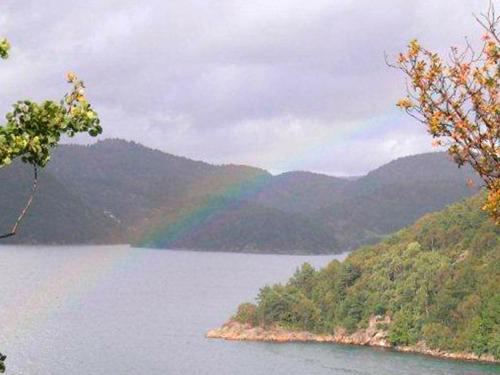 a rainbow in the middle of a lake with mountains at 10 person holiday home in Lindesnes in Spangereid