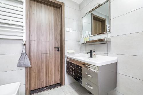 ein Bad mit einem Waschbecken und einem Spiegel in der Unterkunft Qingdao Shibei·Qingdao Carrefour· in Qingdao