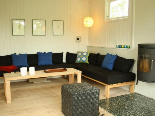 Hornsvedにある4 person holiday home in J gersprisのリビングルーム(黒いソファ、テーブル付)