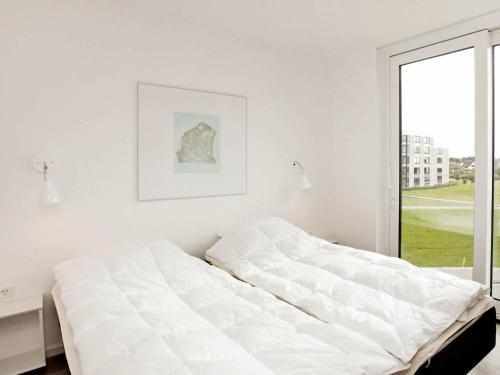 a white bedroom with a bed and a window at One-Bedroom Holiday home in Wendtorf 3 in Wendtorf