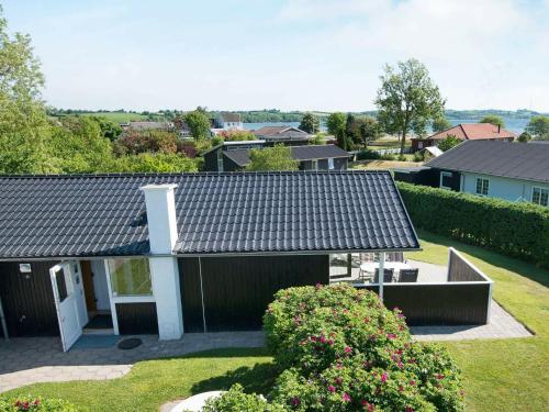 ein Haus mit schwarzem Dach und einigen Büschen in der Unterkunft 4 person holiday home in Broager in Broager