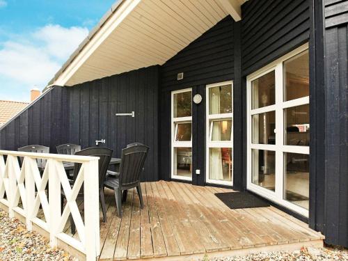 Casa negra con terraza de madera con sillas en 5 person holiday home in GROEMITZ, en Grömitz
