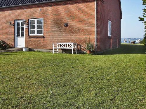 uma casa de tijolos com um banco no quintal em 4 person holiday home in Egernsund em Egernsund