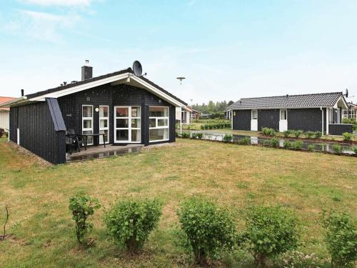 a black house with a yard in front of it at 6 person holiday home in GROEMITZ in Grömitz