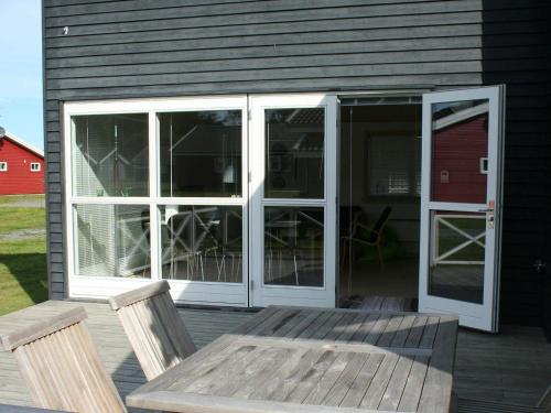 a screened in porch with a wooden table and chairs at 6 person holiday home in Gudhjem in Gudhjem