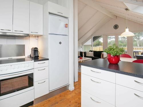 Ålbækにある6 person holiday home in lb kのキッチン(白いキャビネット、黒いカウンタートップ付)