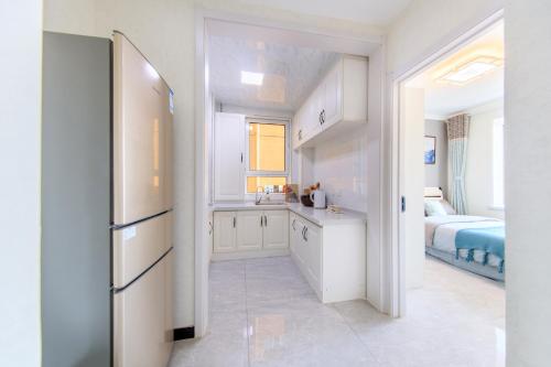 a kitchen with a refrigerator and a bedroom with a bed at Baoding Lianchi·Baoding East Station· in Baoding