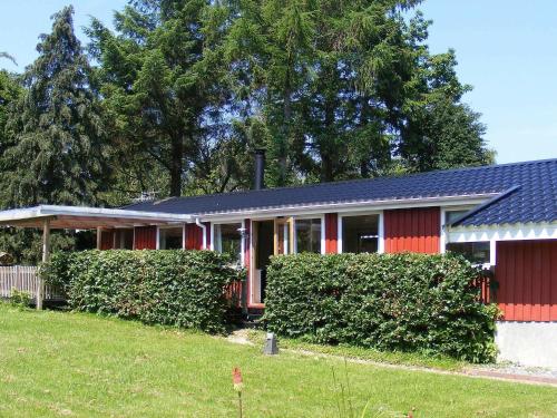 a red house with bushes in front of it at 4 person holiday home in Vordingborg-By Traum in Vordingborg