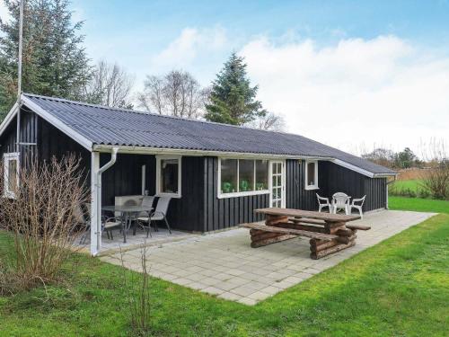 un cobertizo negro con una mesa de picnic y un banco de picnic en 6 person holiday home in S by en Sæby