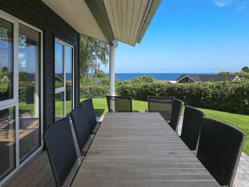 a wooden table with chairs on a porch with the ocean at 16 person holiday home in Alling bro in Rygård Strand