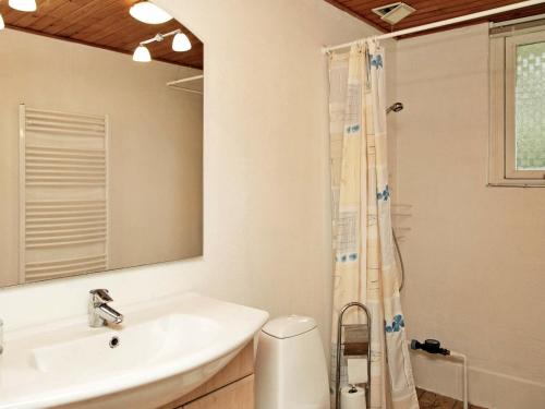 ein weißes Badezimmer mit einem Waschbecken und einem Spiegel in der Unterkunft Three-Bedroom Holiday home in Humble 12 in Humble