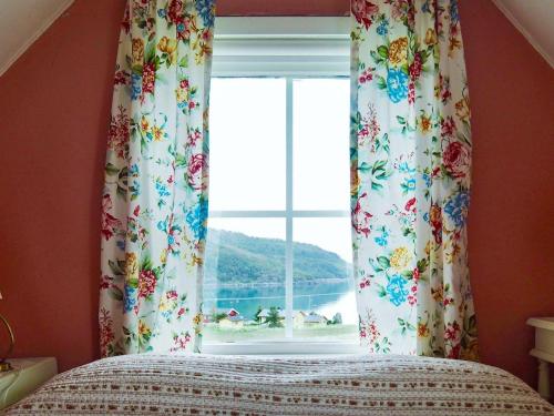 - une chambre dotée d'une fenêtre avec des rideaux fleuris dans l'établissement Three-Bedroom Holiday home in Skatvik, à Seljesletta