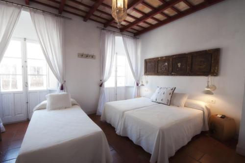 a bedroom with two beds and two windows at Benali Guest House in Tarifa