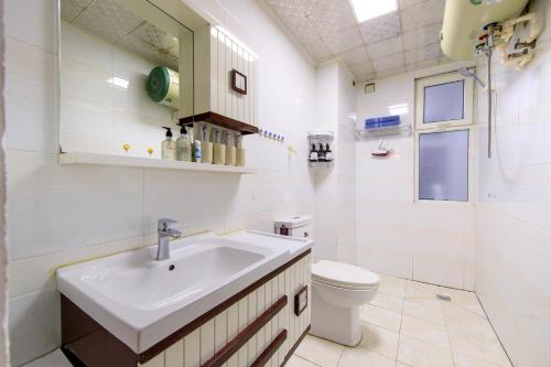 Baño blanco con lavabo y aseo en Baoding Jingxiu·Beiguo Shopping Mall·, en Baoding