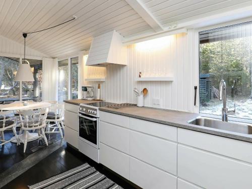 cocina con armarios blancos, fregadero y mesa en 6 person holiday home in lb k en Ålbæk