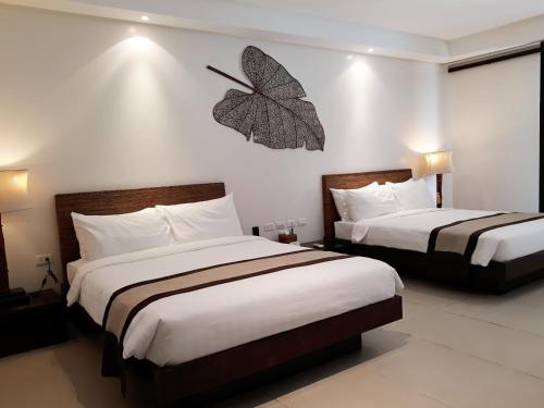 two beds in a hotel room with a butterfly on the wall at Kamana Sanctuary Resort & Spa in Olongapo