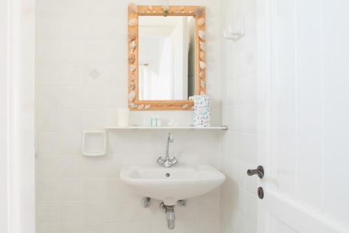 Baño blanco con lavabo y espejo en Alkionides Studios, en Koufonisia