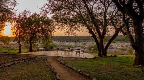 a patio with tables and chairs in a park at Mjejane River Lodge in Hectorspruit