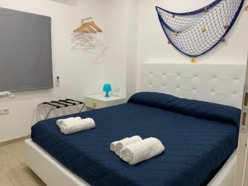 een slaapkamer met een blauw bed en handdoeken bij Arcorosa Apartment in Cefalù