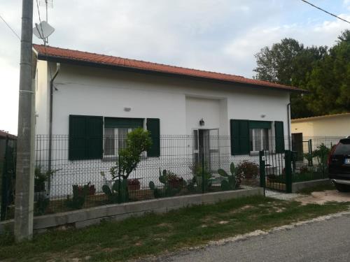 a white house with green shutters and a fence at Casa Melissa in Savio di Ravenna