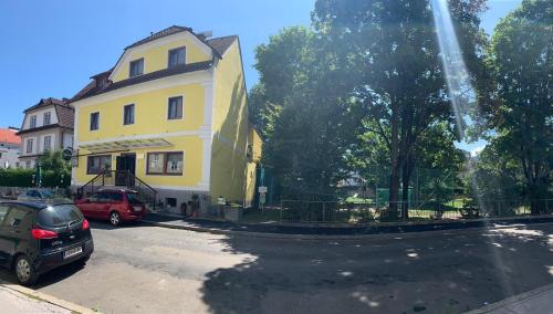 ein gelbes Haus mit Autos auf einem Parkplatz in der Unterkunft Gasthof Knezevic in Leoben