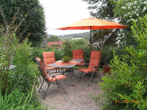 uma mesa e cadeiras com um guarda-sol num jardim em Ferienwohnung Kunze em Obernsees