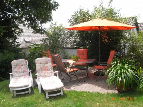 un patio con mesa, sillas y sombrilla en Ferienwohnung Kunze en Obernsees