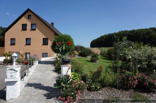 ein Haus mit einem Garten mit Blumen davor in der Unterkunft Ferienwohnung Penning in Oberfellendorf