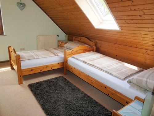 two beds in a wooden room with a window at Haus Burgblick in Obertrubach